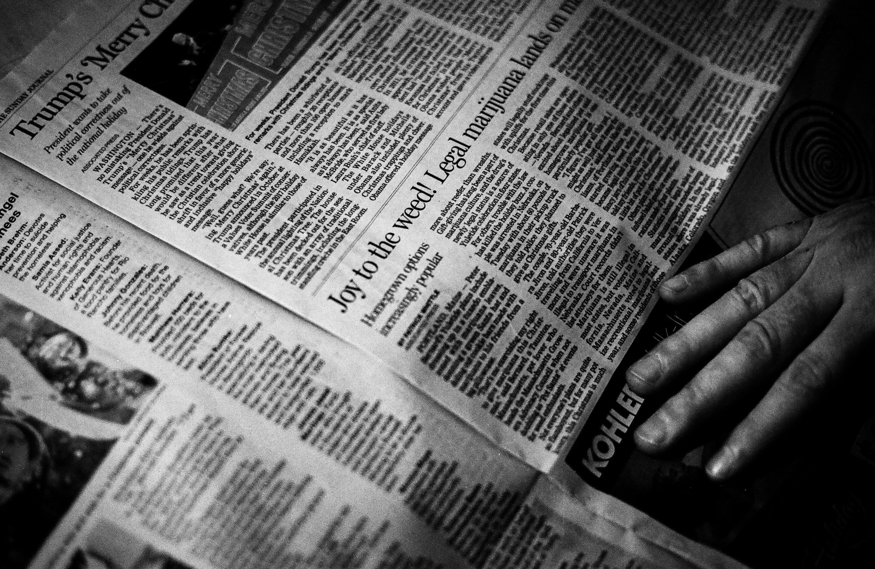 Person's right hand near newspaper